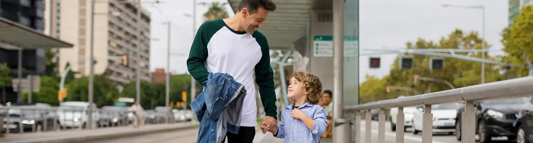 Father and small child walking near metro stop and smiling at each other