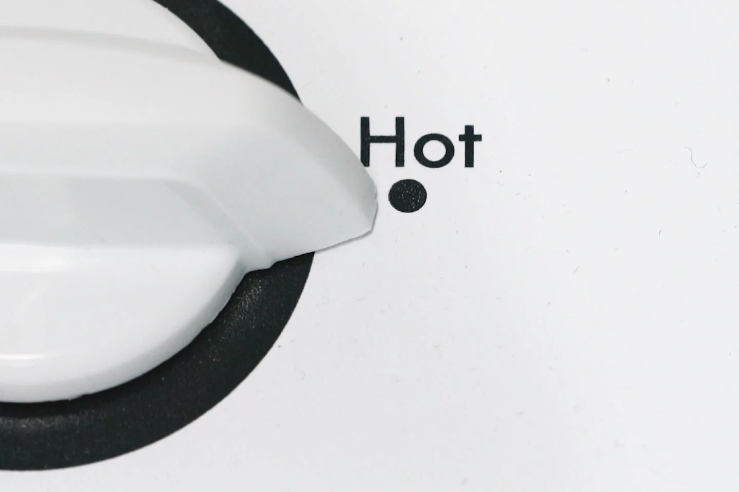 Close-up of white dial set to "Hot" on washing machine.
