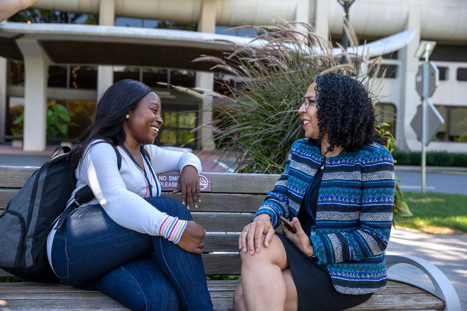Dr. Inginia Genao, vice dean of diversity, equity and belonging, talks with a student on a bench outside the college.