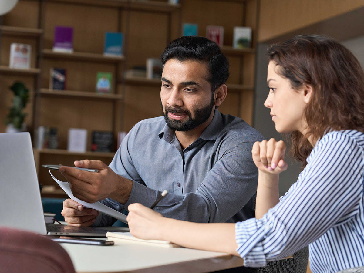  A man and woman collaborate on a laptop, discussing program execution solutions.
